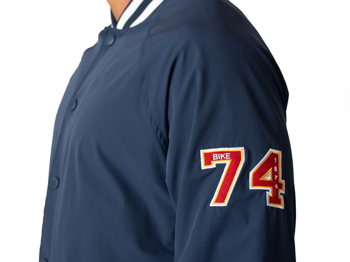 Blue vintage Varsity Bomber Jacket includes tackle twill "74" on the left sleeve, rib-knit collar and cuff, snap front closure, front hand pocket and interior chest pocket, and interior mesh lining.